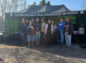 Uczniowie i nauczyciele wyprowadzający psy pod banerem schroniska