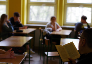 uczniowie w klasie podczas czytania przez nauczyciela książki