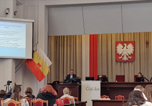 Lekarz ze szpitala w Wieluniu stoi przy mównicy w Dużej Sali Obrad Urzędu Miasta Łodzi i prezentuje wykład na temat raka szyjki macicy