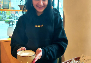Uczennica z fiżanką kawy, którą samodzielnie przygotowała -wzór serduszka na kawie
