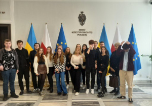 uczniowie przy flagach Polski, Unii Europejskiej oraz Ukrainy w holu Senatu Rzeczpospolitej
