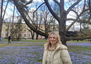 Uczennica przed Dębem Fabrykantem w otoczeniu kwitnących cebulic w Parku im. ks. bp. Klepacza w Łodzi
