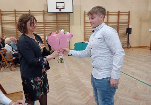 Z okazji Dnia Edukacji Narodowej uczeń wręcza kwiaty Pani Dyrektor