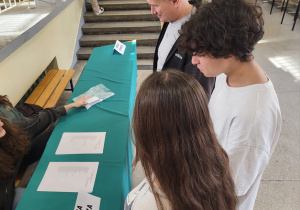 Uczniowie z nauczycielem odbierają karty do głosowania